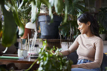 Smiling businesswoman using laptop at loft office - BSZF02268