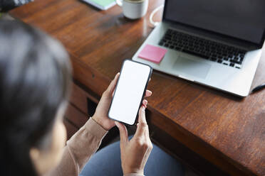 Hands of businesswoman holding smart phone with blank screen at loft office - BSZF02275