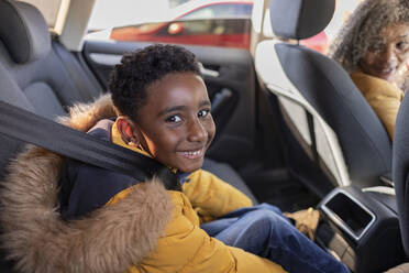 Happy boy sitting with grandmother in car - JCCMF09853