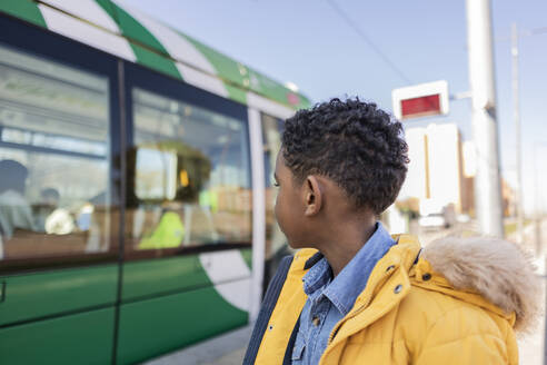 Junge im Parka-Mantel schaut auf die Straßenbahn - JCCMF09871