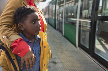 Grandmother standing with grandson at tram station - JCCMF09873