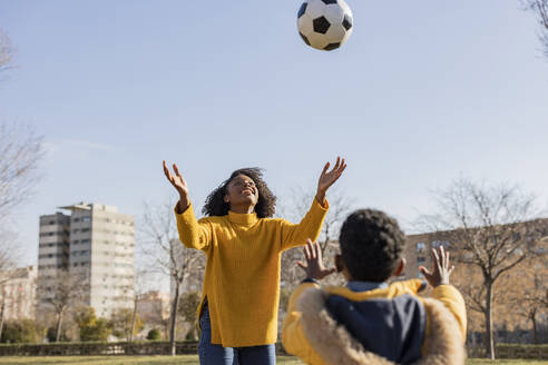 Verspielte Mutter und Sohn beim Ballfangen im Park - JCCMF09882