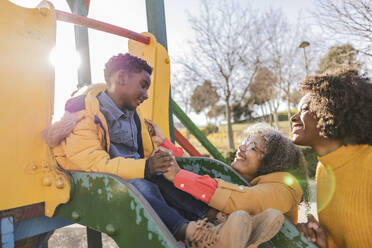 Junge hat Spaß mit Familie auf der Rutsche auf dem Spielplatz - JCCMF09911