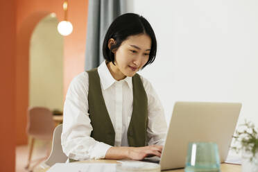 Smiling businesswoman with short hair working on laptop in office - EBSF02937