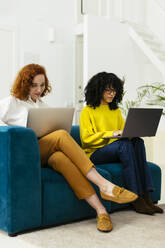 Geschäftsfrauen arbeiten am Laptop auf dem Sofa im Büro - EBSF02955