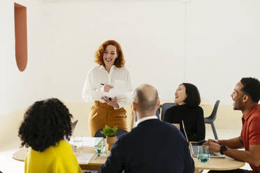 Glückliche multirassische Geschäftsfrau, die mit Kollegen in einer Besprechung im Büro diskutiert - EBSF02979