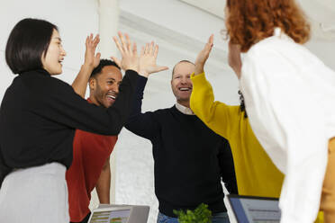 Happy multiracial colleagues giving high-five in office - EBSF02985