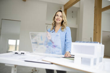 Nachdenklicher Architekt mit futuristischem Tablet-PC auf der Baustelle - HMEF01601