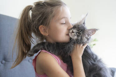 Mädchen mit geschlossenen Augen küsst Katze zu Hause - SVKF01342