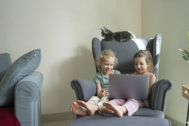 Mädchen, die zu Hause im Sessel sitzend den Laptop beobachten - SVKF01361