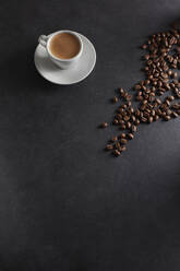 Tasse Espresso und geröstete Kaffeebohnen auf schwarzem Hintergrund - KSWF02326