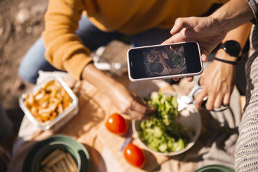 Hand eines Mannes, der seine Mahlzeit mit seinem Smartphone fotografiert - PCLF00274