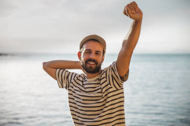 Lächelnder Mann mit erhobener Hand und gestreiftem T-Shirt - PCLF00279