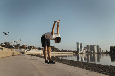 Young man stretching hands before run on footpath - ANNF00085