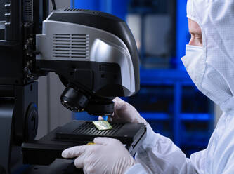 Scientist checking circuit board semiconductor through microscope in laboratory - CVF02341