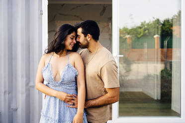 Affectionate couple standing outside container home - JJF00427