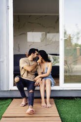Romantisches Paar genießt zusammen sitzen außerhalb Container Haus - JJF00433