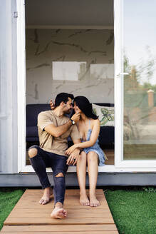Romantic couple enjoying together sitting outside container home - JJF00433