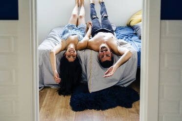 Smiling couple enjoying together lying on bed at home - JJF00443