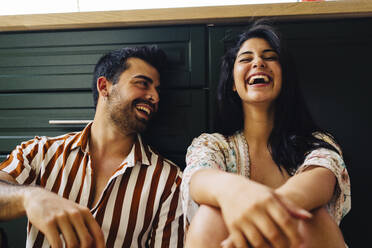 Paar lacht zusammen vor einer Schublade zu Hause - JJF00474