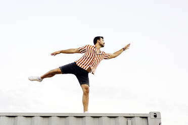 Man dancing on top of container home - JJF00497