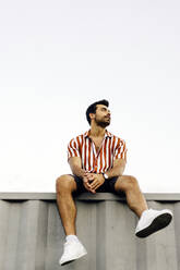 Thoughtful man sitting on top of container home - JJF00498