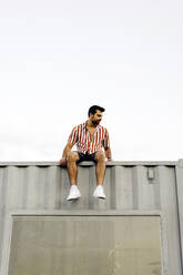 Man sitting on top of container home - JJF00499