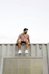 Mann sitzt auf dem Dach eines Containerhauses - JJF00499