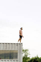Man standing on top of container home - JJF00500