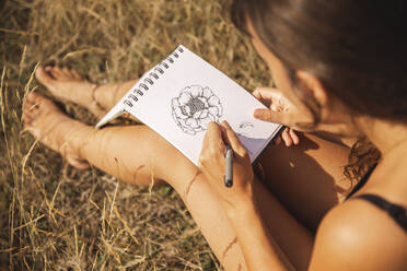 Junge Frau zeichnet Blume auf Skizzenblock - PCLF00288