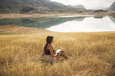 Young woman with sketch pad sitting in front of Rama Lake - PCLF00289