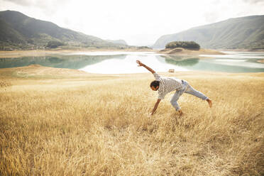 Man doing cartwheel in front of lake - PCLF00300