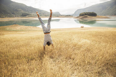 Mann macht Handstand auf trockenem Gras - PCLF00301