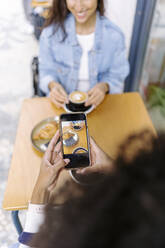 Junge Frau fotografiert Essen und Trinken mit ihrem Smartphone - JJF00509