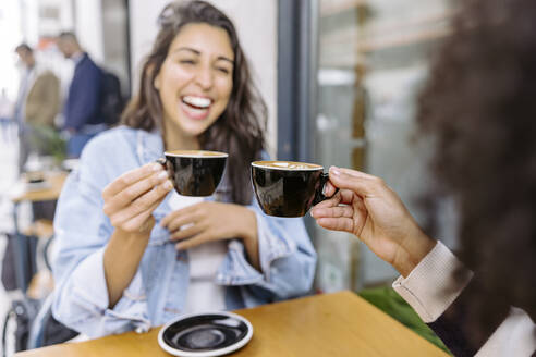 Cheerful friends toasting coffee cup and enjoying at sidewalk cafe - JJF00516