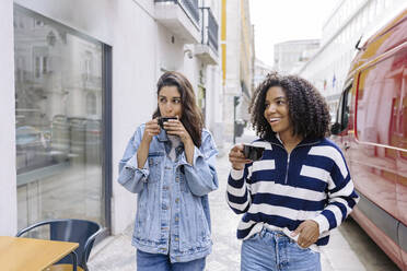 Happy friends with coffee cups walking at footpath - JJF00522