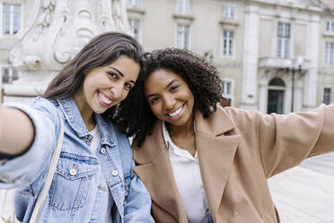 Happy friends taking selfie in front of building - JJF00555