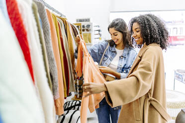 Happy young multiracial friends shopping together at clothing store - JJF00567