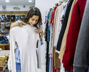 Young woman checking clothes at store - JJF00573