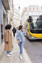 Junge Frau mit Freund schaut auf Bus - JJF00593