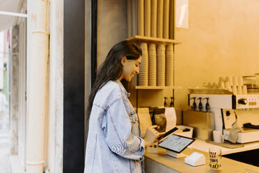 Glückliche junge Frau, die ein Smartphone benutzt und über einen Tablet-PC in einem Café bestellt - JJF00608