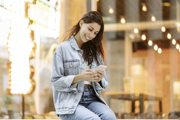 Happy young woman using smart phone - JJF00631