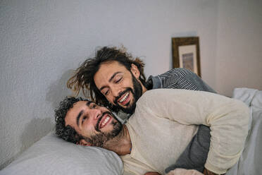 Happy gay couple cuddling in bed at home - GDBF00042