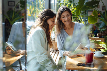 Happy women sharing tablet PC in cafe - JOSEF17569