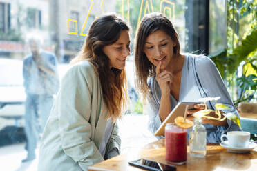 Smiling women sharing tablet PC in cafe - JOSEF17570