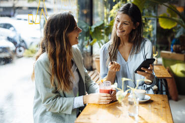 Woman with friend using credit card and mobile phone in cafe - JOSEF17574