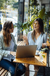 Geschäftsfrauen, die mit einem Laptop in einem Café sitzen und diskutieren - JOSEF17579