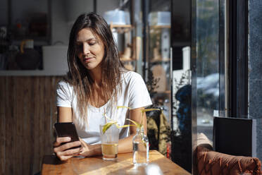 Woman using smart phone in cafe - JOSEF17596