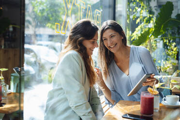 Glückliche Frau, die sich einen Tablet-PC im Café teilt - JOSEF17619