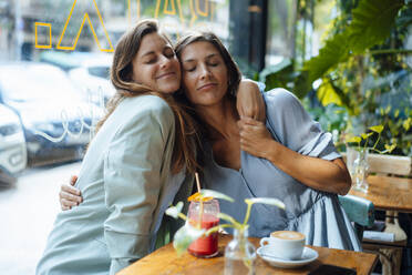 Lächelnde Freunde, die sich im Café in den Armen liegen - JOSEF17623